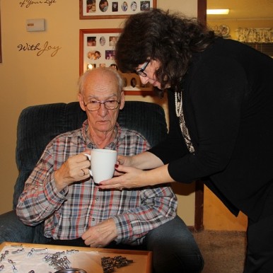 Caregiver Sheri Zschocher helping husband Bob with coffee