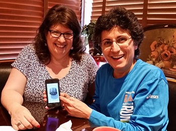 Sheri Zschocher and Brenda Avadian looking at a photo of Bob Z's ladybug carving