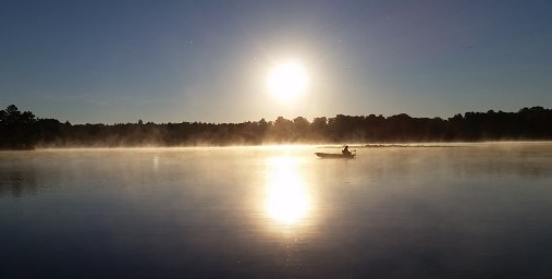 Early morning sunrise and fisherman on a boat on a Wisconsin lake.