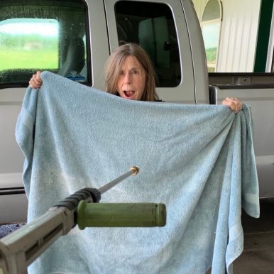 Ann Williams who lives with Alzheimer's holds up a bath towel has her caregiver husband aims a pressure washer - caregiver humor