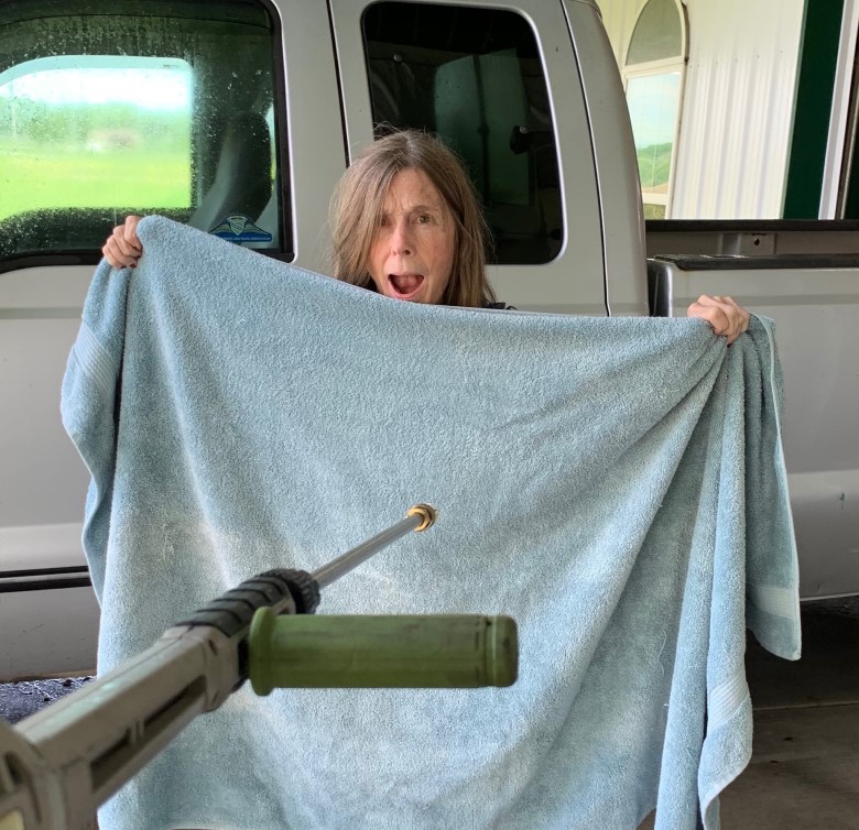 Ann Williams who lives with Alzheimer's holds up a bath towel has her caregiver husband aims a pressure washer - caregiver humor