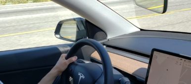 Driving a Tesla with hands on steering wheel.
