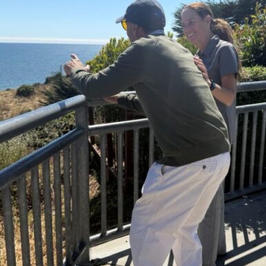 Melissa Mirabello smiling at an older man looking out to the sea below - TCV