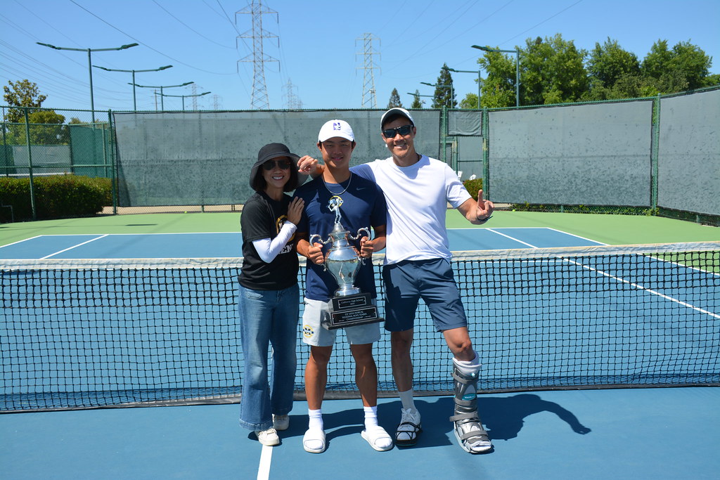 Image of Ed Han with leg injury and his wife and son at a tennis court